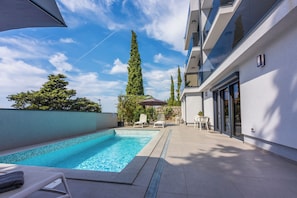 Ein Pool mit Liegestühlen, einer Pergola und hohen Bäumen.