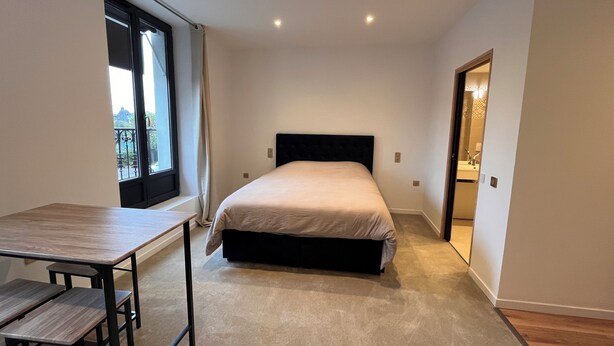Un dormitorio con cama, ventana, escritorio y puerta que da a un baño.
