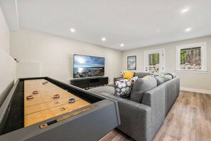 Une table de billard dans un salon, avec un canapé et un tableau accroché au mur.