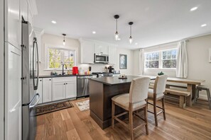 A modern kitchen with white cabinets, stainless steel appliances, a central island, and pendant lighting. - Summit Ridge - New 5BR Home in Lincoln - Near Trails, River & Loon (Lincoln)