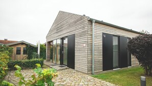 Een modern huis met een schuin dak, een verharde oprit en een verzorgde tuin.