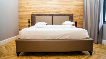 A bed with a wooden headboard, a wooden floor, and a window with curtains.