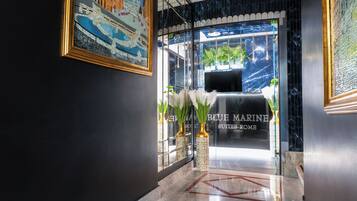 Un vestíbulo de hotel con una recepción, una obra de arte en mosaico y un suelo de mármol.