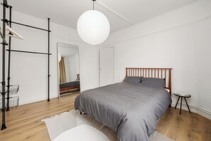 Un dormitorio con una cama, una lámpara de pie, un espejo y una mesita.