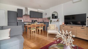 Eine moderne Küche mit Essbereich, einer Couch, einem Fernseher und einer dekorativen Vase.