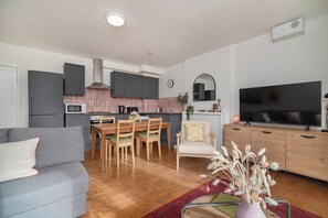 Eine moderne Küche mit Essbereich, einer Couch, einem Fernseher und einer dekorativen Vase.