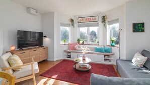 Ein modernes Wohnzimmer mit Fernseher, Sofa und einem roten Teppich.