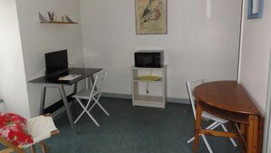 A small room with a desk, a chair, a microwave, a shelf with pens, and a painting on the wall. - Poitiers Centre Cathédrale Studio 20 m² (215 sq. ft.) (Poitiers)