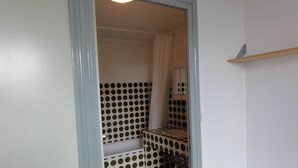 A bathroom with a polka dot tile pattern, a mirror, and a wooden shelf. - Poitiers Centre Cathédrale Studio 20 m² (215 sq. ft.) (Poitiers)