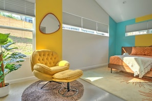 A bedroom with a bed, a yellow armchair, a large mirror, and a potted plant. - Modern Designer Retreat (Chattanooga)