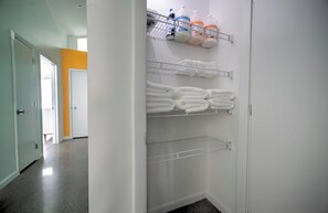A walk-in closet with shelves for folded towels and storage bins. - Modern Designer Retreat (Chattanooga)
