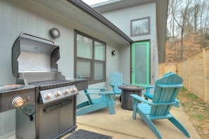 A backyard with a grill, two Adirondack chairs, a table, and a green door. - Modern Designer Retreat (Chattanooga)