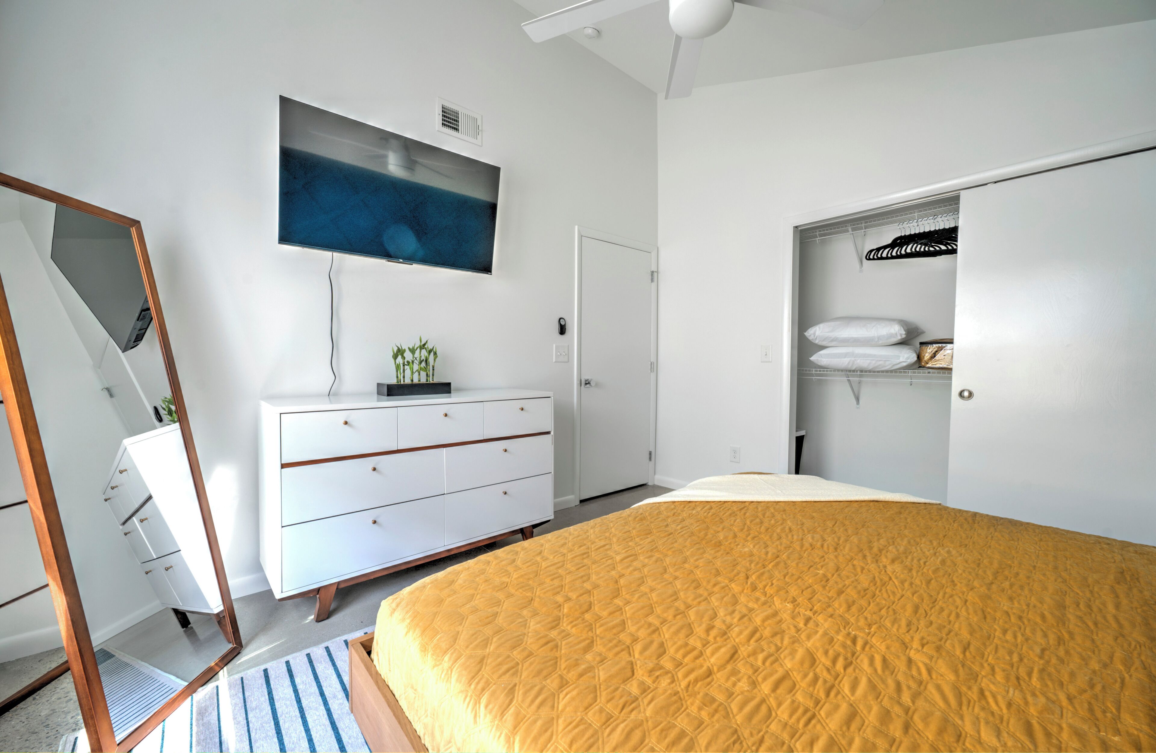 Une chambre à coucher comprenant un lit, une commode, un téléviseur et une armoire.