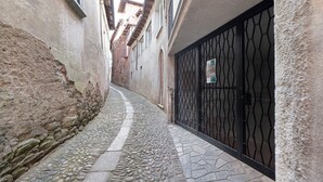 A narrow alleyway with cobblestone pavement, stone walls, and a metal gate. - Relax and Recharge in This Refined Oasis of Tranquility (Miasino)