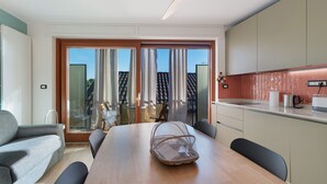 A modern kitchen with a dining area, large sliding glass doors, and a ceiling fan. - Relax and Recharge in This Refined Oasis of Tranquility (Miasino)