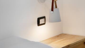 A bedside table with a lamp, a power outlet, and a wooden nightstand.
