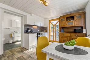 A modern kitchen with white cabinetry, a built-in oven, and a dining area with a table and chairs. - Apartment “Echaztal” with Private Terrace and Garden (Pfullingen)
