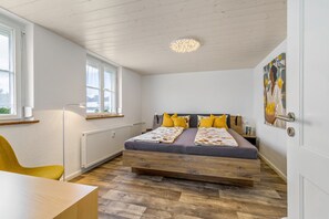 Un dormitorio con cama, radiador, ventana y puerta.