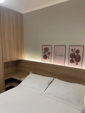 Ein Schlafzimmer mit einem hölzernen Kopfteil, einem Bett mit weißer Bettwäsche und drei gerahmten Wandbildern.