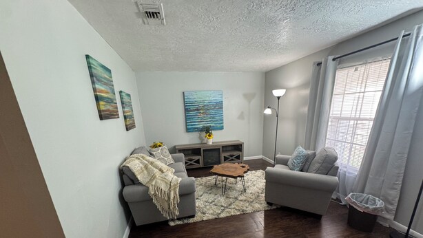 A living room with a sofa, a coffee table, a lamp, and artwork on the walls. - Apartment near Hobby Airport (Houston)