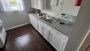 A kitchen with white cabinets, a stainless steel sink, a coffee maker, and a blender. - Apartment near Hobby Airport (Houston)