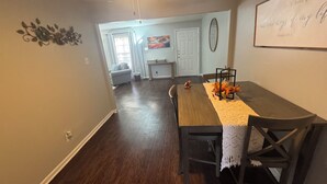 A dining area with a wooden table, chairs, a ceiling fan, and a wall-mounted light fixture. - Apartment near Hobby Airport (Houston)