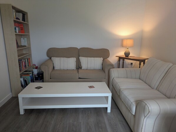 A living room with a sofa set, a coffee table, a side table with a lamp, and a bookshelf.
