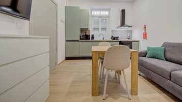 Une cuisine compacte avec une table et des chaises, un canapé gris et un téléviseur sur le côté gauche.