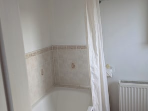 Rincón de un baño con azulejos color beige y un radiador blanco.
