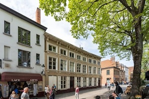 Eine Straße mit Gebäuden, einem Baum und Fußgängern.