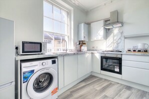 A modern kitchen with a built-in washer, oven, and microwave.