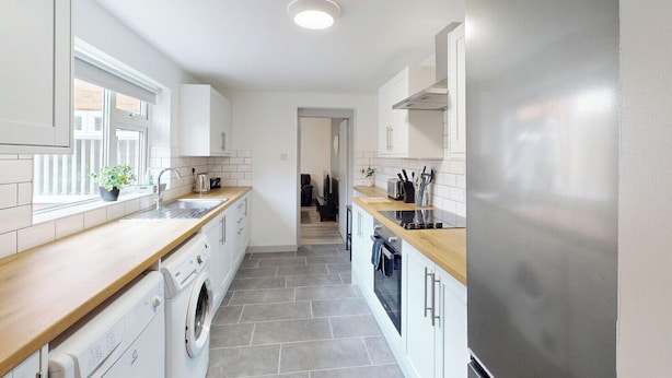 A narrow kitchen with white cabinets, a washing machine, and a dishwasher. - House Sleeps 10 With Wifi (Sunderland)