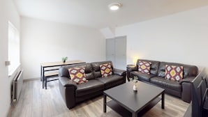A modern living room with two leather sofas, a coffee table, and a small table with a plant. - House Sleeps 10 With Wifi (Sunderland)