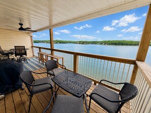 A covered outdoor deck with wooden furniture, a ceiling fan, and a view of a lake. - Front Row to the Main Channel - 3BR walk in unit! (Osage Beach)