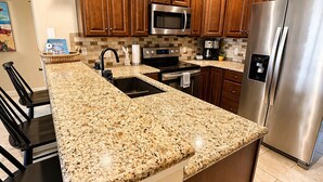 A kitchen with granite countertops, stainless steel appliances, wooden cabinets, and a central island with bar stools. - Front Row to the Main Channel - 3BR walk in unit! (Osage Beach)
