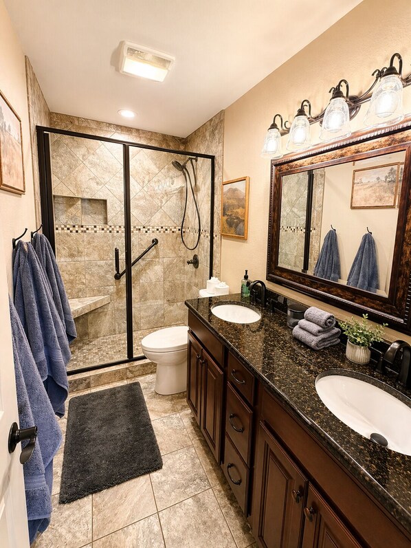 A bathroom with a glass shower enclosure, a sink, a toilet, and a large mirror. - Front Row to the Main Channel - 3BR walk in unit! (Osage Beach)