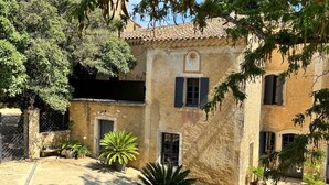 A courtyard with a building, potted plants, and outdoor furniture. - Holiday Home 'L'Essentiel' with Shared Pool, Shared Garden and Wi-Fi (Lieuran-lès-Béziers)