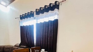 Un comedor con una mesa de mármol, sillas de madera, un florero de cristal y cortinas oscuras.