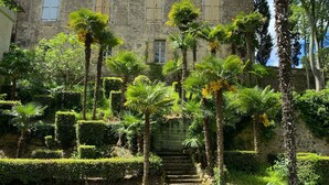 A historic building with a central tower, surrounded by a well-maintained garden with palm trees and hedges. - Holiday Home 'Présbytère' with Shared Pool, Shared Garden and Wi-Fi (Lieuran-lès-Béziers)
