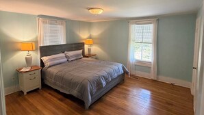 A bedroom with a bed, two bedside tables, a ceiling light, and two windows with curtains. - Spacious Home with fenced in yard, close to everything, great for families (Rutherfordton)