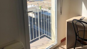 Un balcón con vistas a la playa, una silla y una mesa.