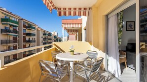 A balcony with a round table and chairs, a potted plant, and a striped awning. - Home2Book Fresh Beach & Pool Apt Los Cristianos (Los Cristianos)