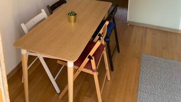 A dining area with a wooden table and chairs, a radiator, and a potted plant on a shelf.
