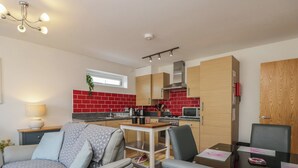 Un espace de vie compact comprenant un coin cuisine, un coin repas et un espace détente avec un canapé et des fauteuils.
