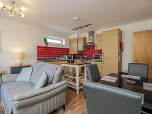 Ein kompakter Wohnbereich mit Küchenzeile, einem Essbereich und einer Sitzecke mit Sofa und Sesseln.