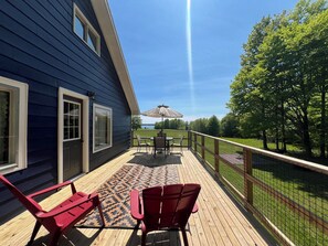 Une terrasse dotée de mobilier d’extérieur, offrant une vue sur un lac et s’ouvrant sur un ciel dégagé.