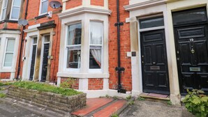 A row of red brick terraced houses with black front doors, numbered 17 and 19, and satellite dishes on the roof. - 17 Fairfield Road (Newcastle-upon-Tyne)