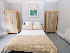 A bedroom with a bed, two wooden wardrobes, a framed picture on the wall, and a grey carpet. - 17 Fairfield Road (Newcastle-upon-Tyne)