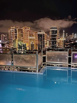 Piscina no terraço com paisagem urbana ao fundo.