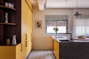 Una cocina moderna con un mueble amarillo, un fregadero y una ventana con persianas.